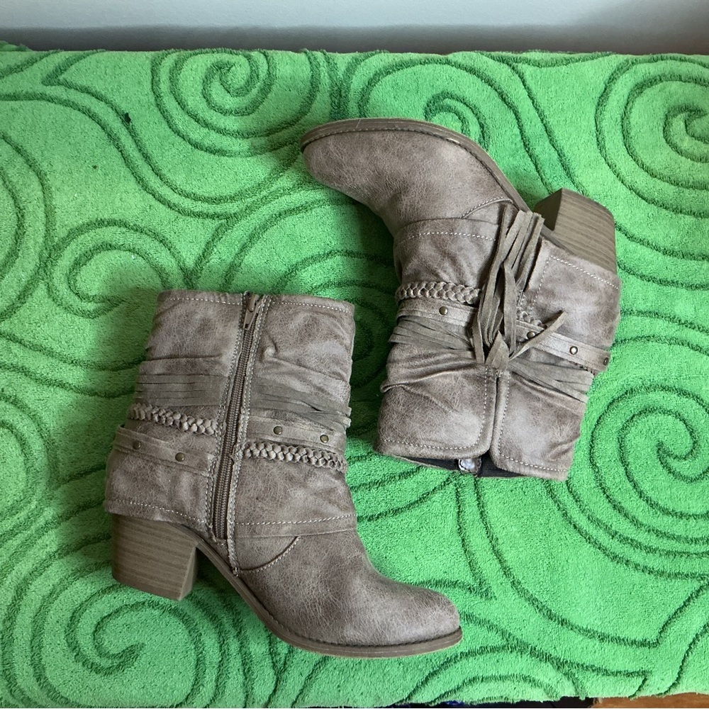 Jellypop taupe booties featuring side zippers, braided details, and fringe.